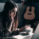 Woman lying on bed, focused on laptop